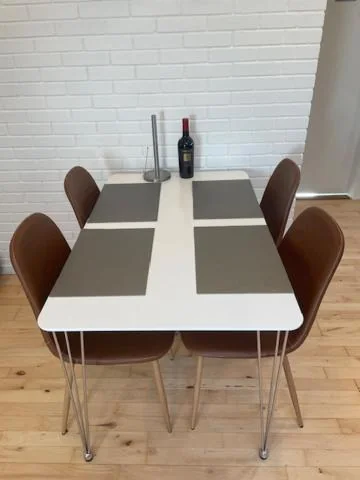 Dækket spisebord med viskestykker, stole og en flaske vin