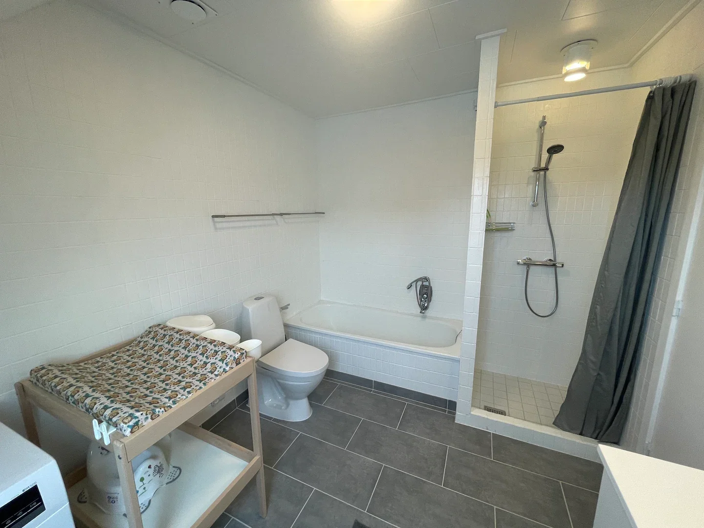 Større badeværelse med badekar, brusekabine og wc