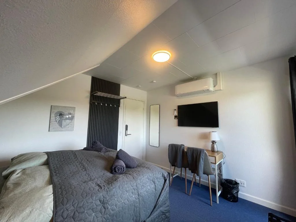 Dobbeltseng under skråt loft med vægmonteret tv
